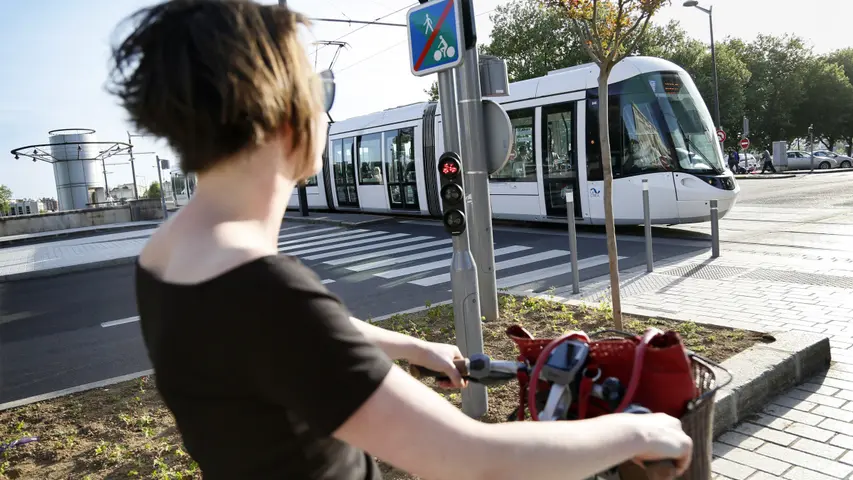 Femme à vélo attendant le passage d'un tramway